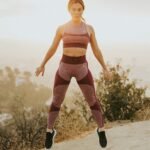 woman jumping above gray sand